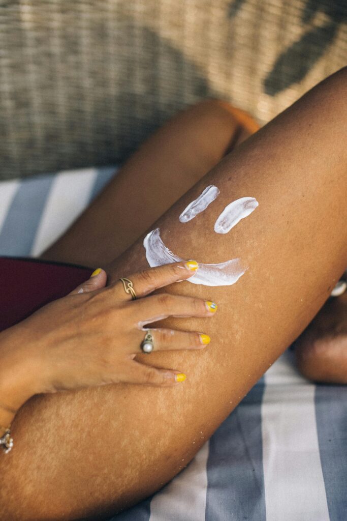 pexels-photo-7466779-7466779 Close-up of a hand applying sunscreen on a leg with a smiley. Sunny and fun outdoor setting.